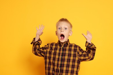 Scared little boy screaming on orange background. Space for text