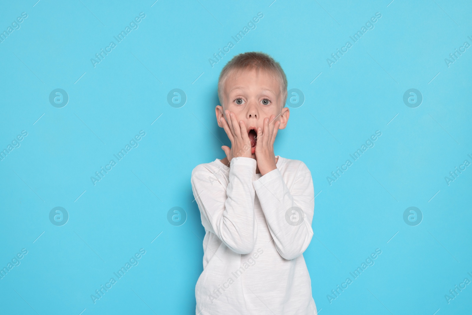 Photo of Scared little boy on light blue background