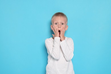 Photo of Scared little boy on light blue background