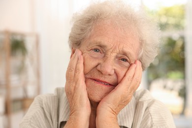 Portrait of beautiful senior woman against blurred background