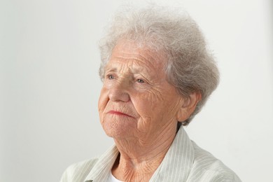 Portrait of senior woman on light grey background, closeup