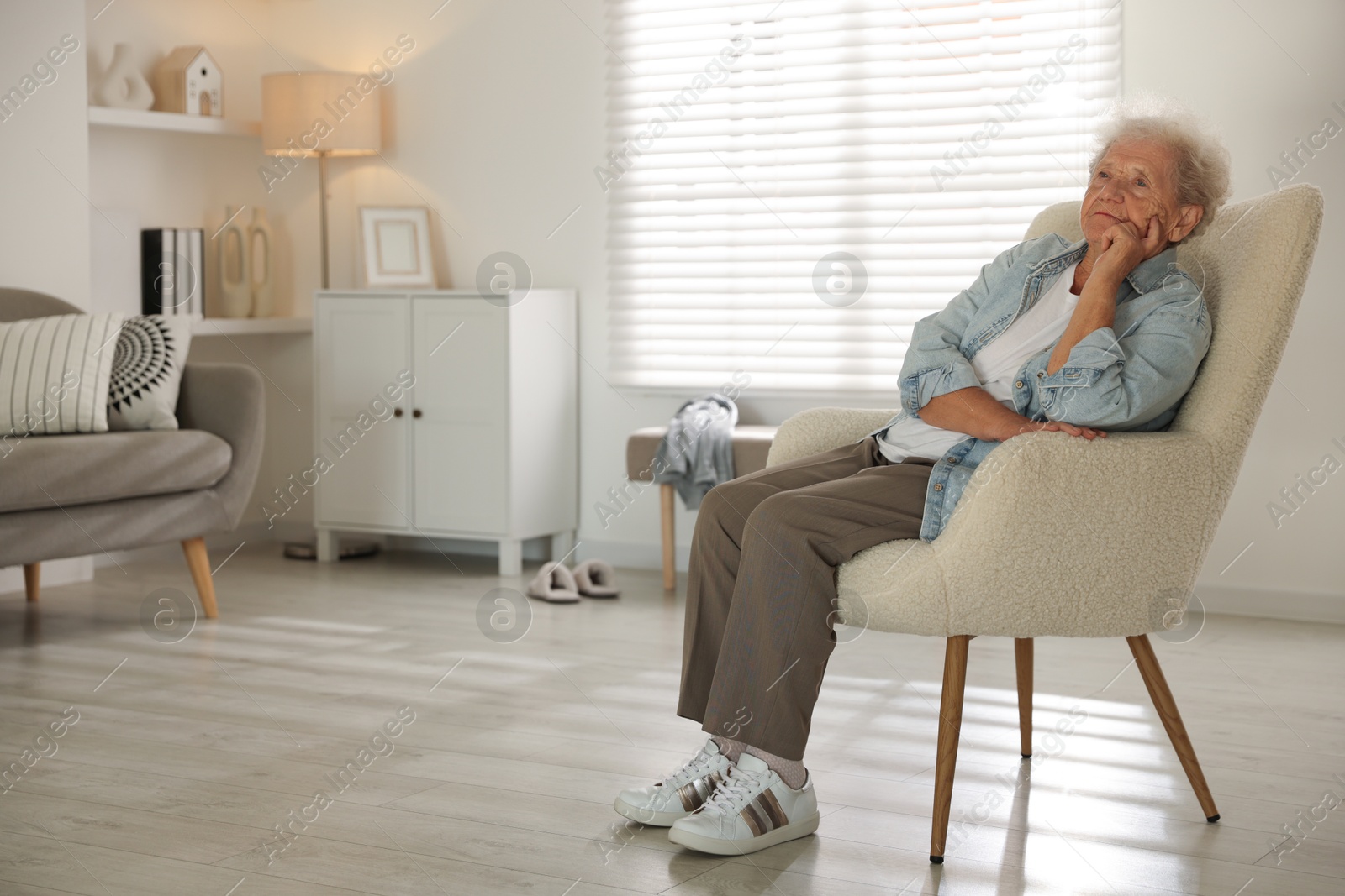 Photo of Loneliness concept. Sad senior woman sitting in armchair at home