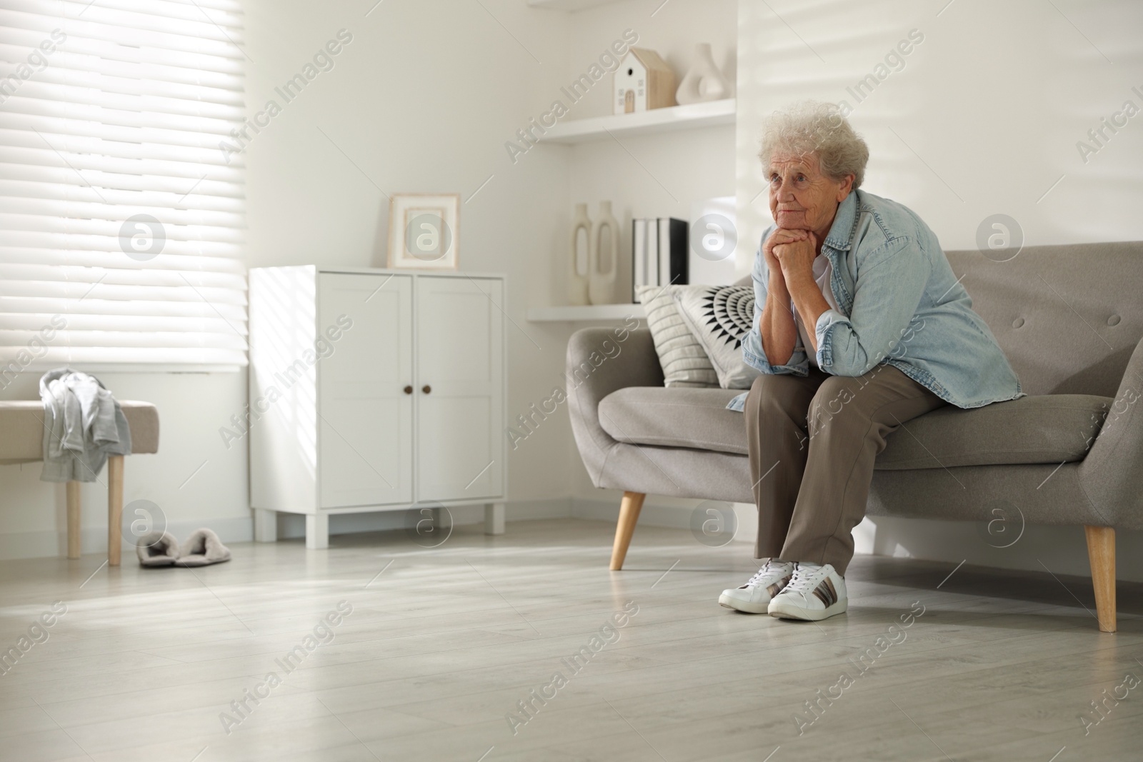 Photo of Loneliness concept. Sad senior woman sitting on sofa at home