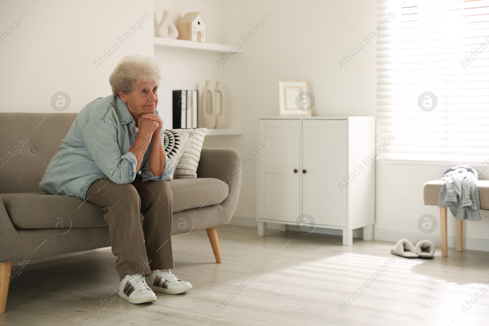 Photo of Loneliness concept. Sad senior woman sitting on sofa at home