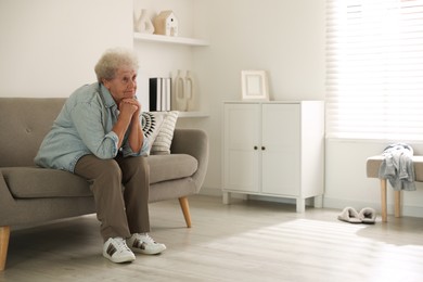 Loneliness concept. Sad senior woman sitting on sofa at home