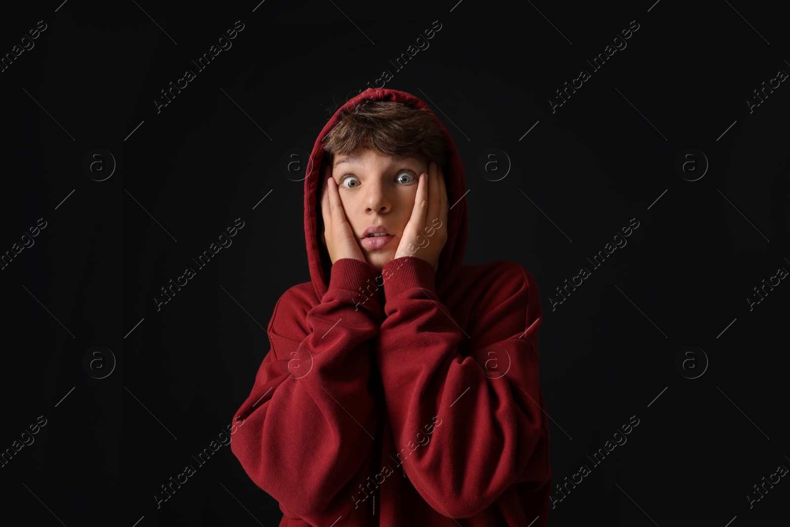 Photo of Portrait of scared teenage boy on black background