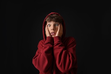 Photo of Portrait of scared teenage boy on black background