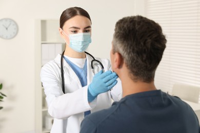 Photo of Doctor examining man's throat in clinic during appointment