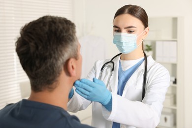 Photo of Doctor examining man's throat in clinic during appointment