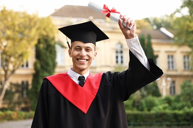 Happy student with diploma after graduation ceremony outdoors