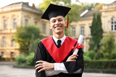 Photo of Happy student with diploma after graduation ceremony outdoors