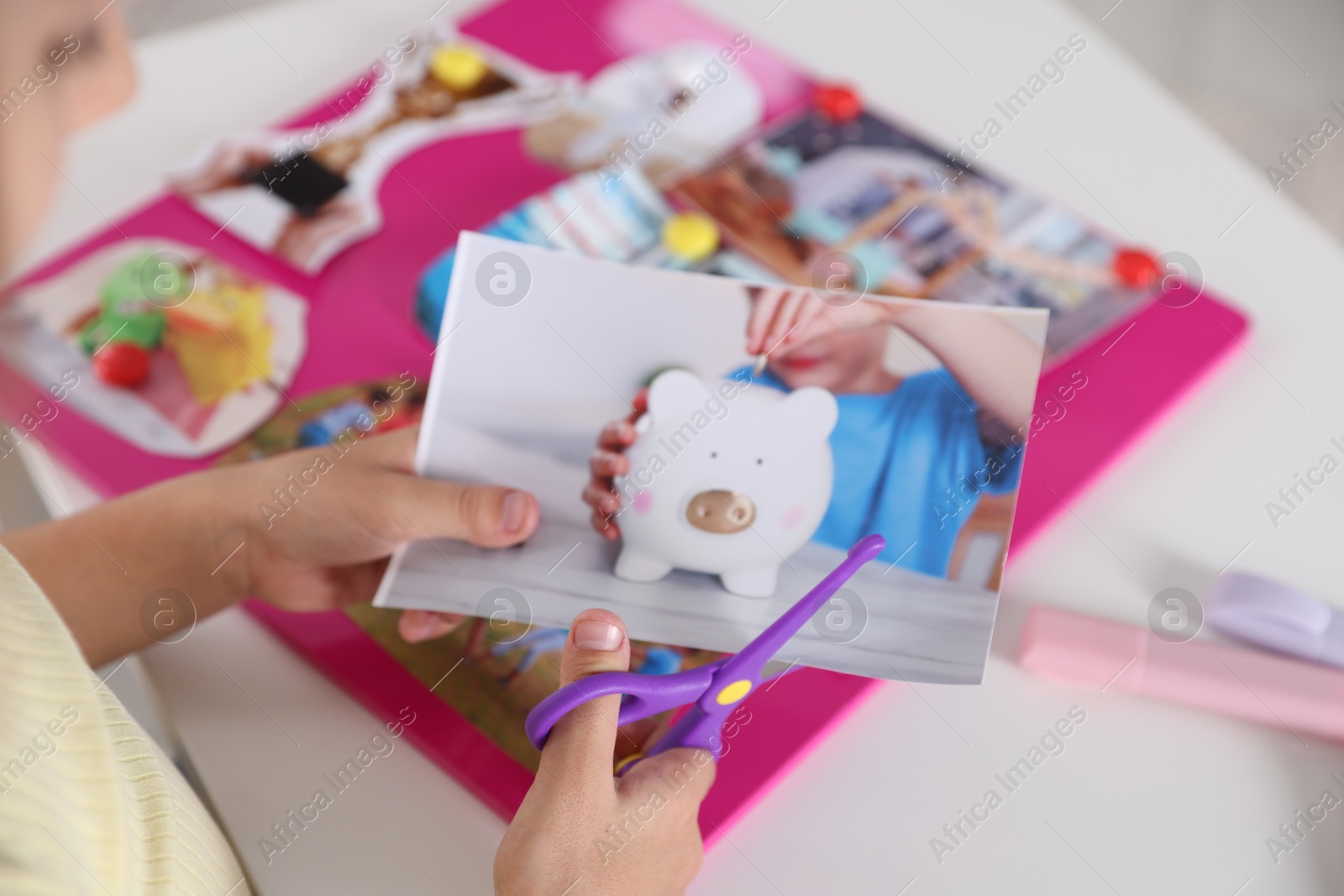 Photo of Creating vision board. Girl cutting out picture at light table, closeup