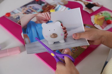 Creating vision board. Girl cutting out picture at light table, closeup