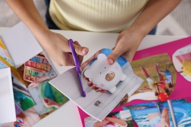 Creating vision board. Girl cutting out picture at light table, closeup