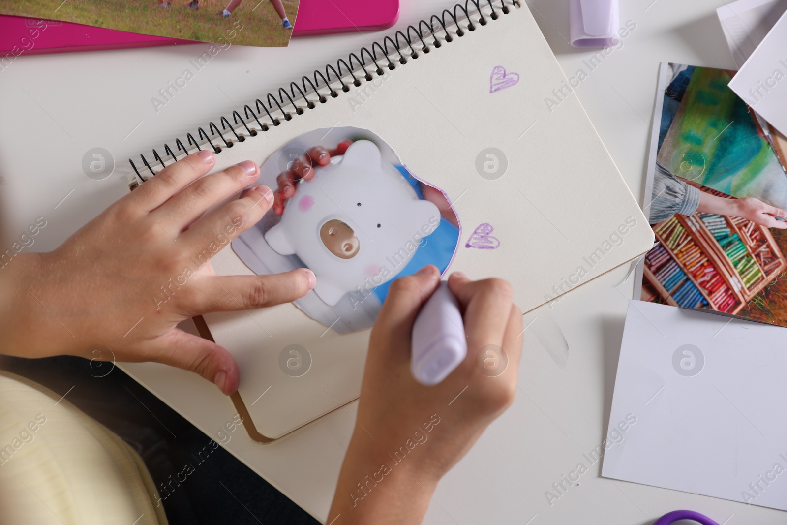 Photo of Creating vision board. Girl outlining picture with violet marker at light table, top view