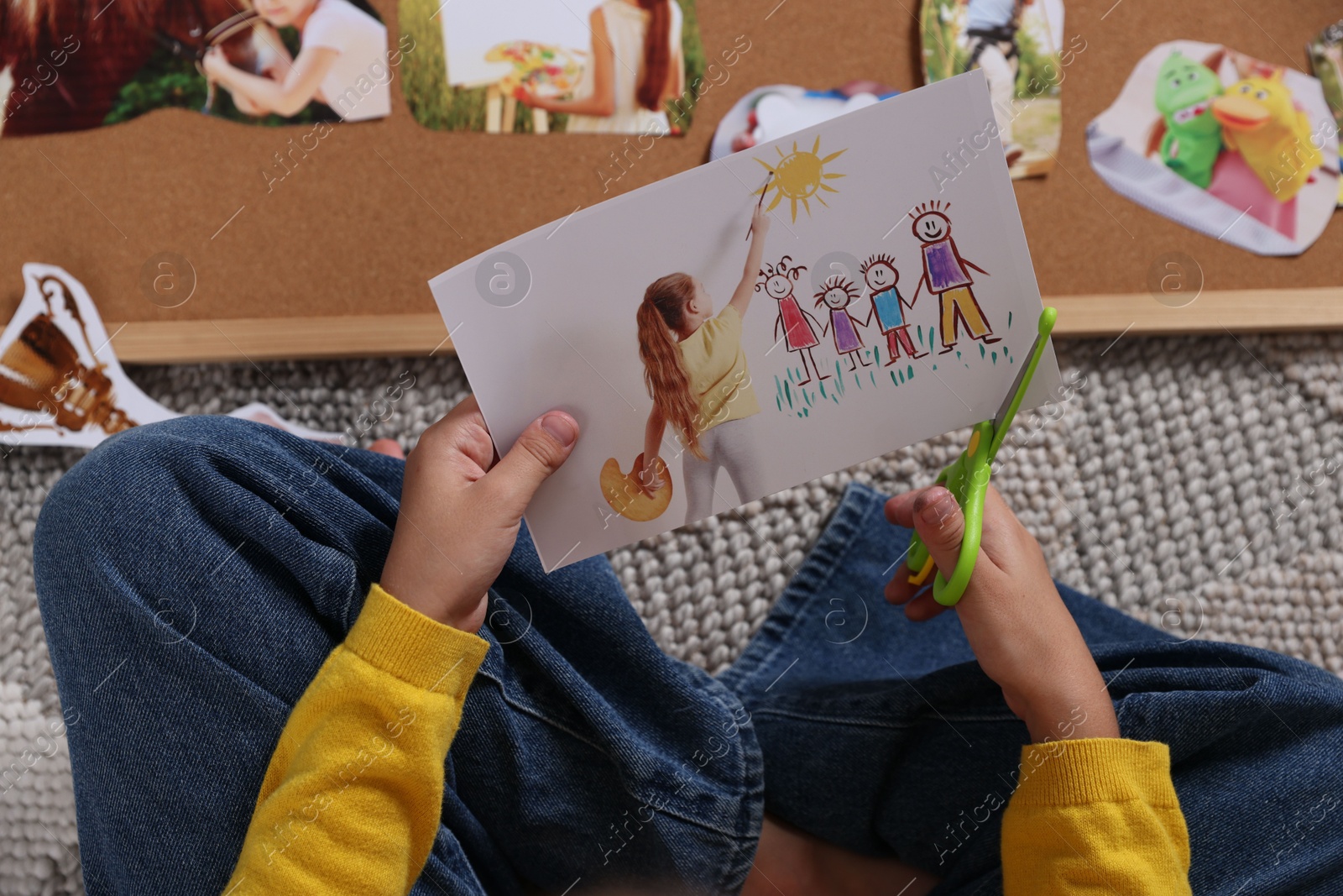 Photo of Creating vision board. Girl cutting out picture on floor, top view