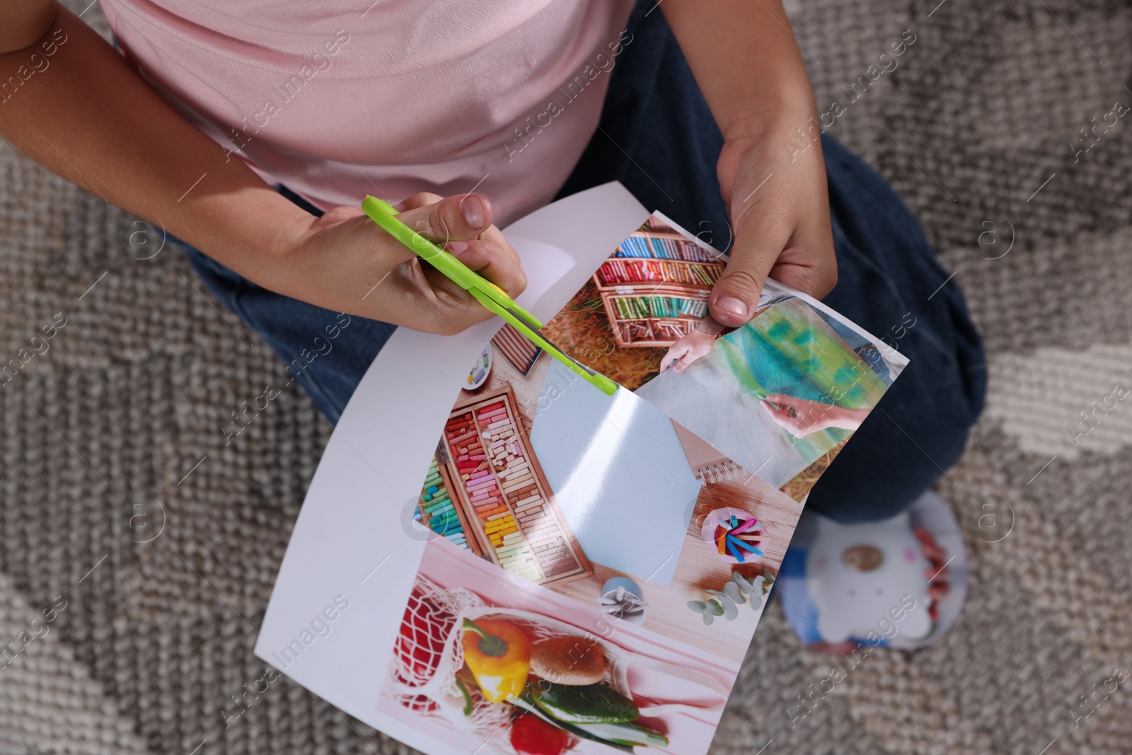 Photo of Creating vision board. Girl cutting out picture on floor indoors, top view