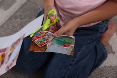 Photo of Creating vision board. Girl cutting out picture on floor indoors, closeup