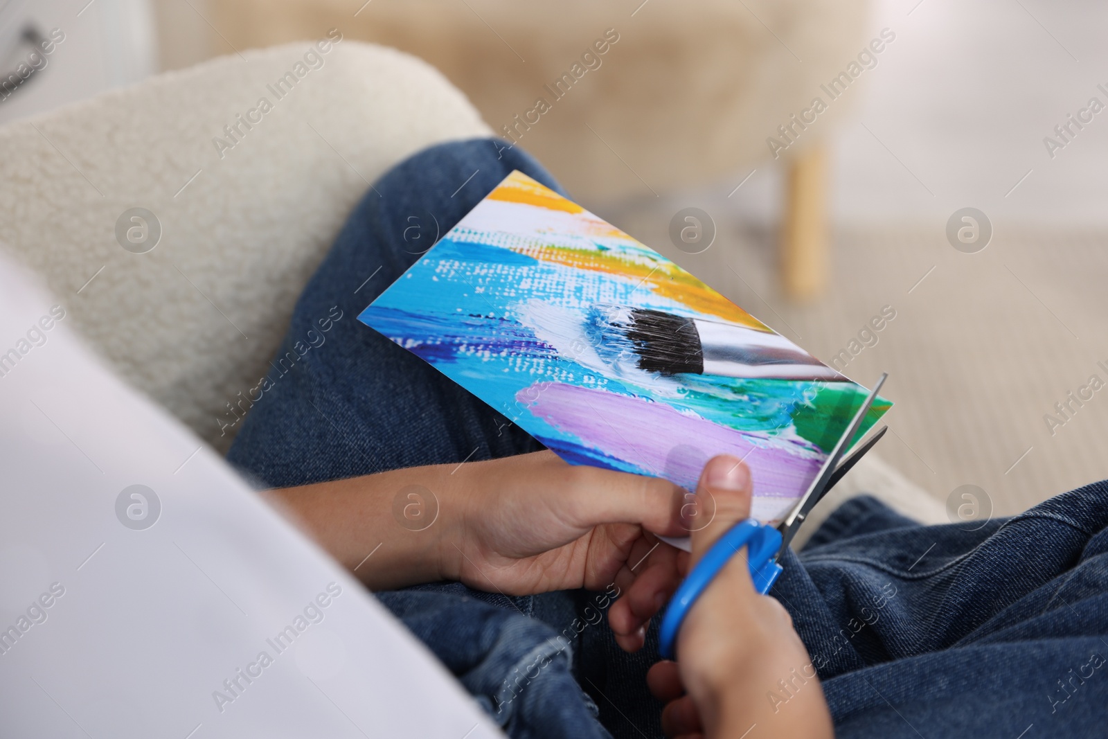 Photo of Creating vision board. Girl cutting out picture in armchair, closeup