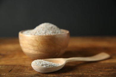 Photo of Fresh rye bran in bowl and spoon on wooden table, closeup