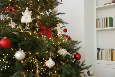 Photo of Christmas tree decorated with beautiful ornaments and lights indoors, closeup