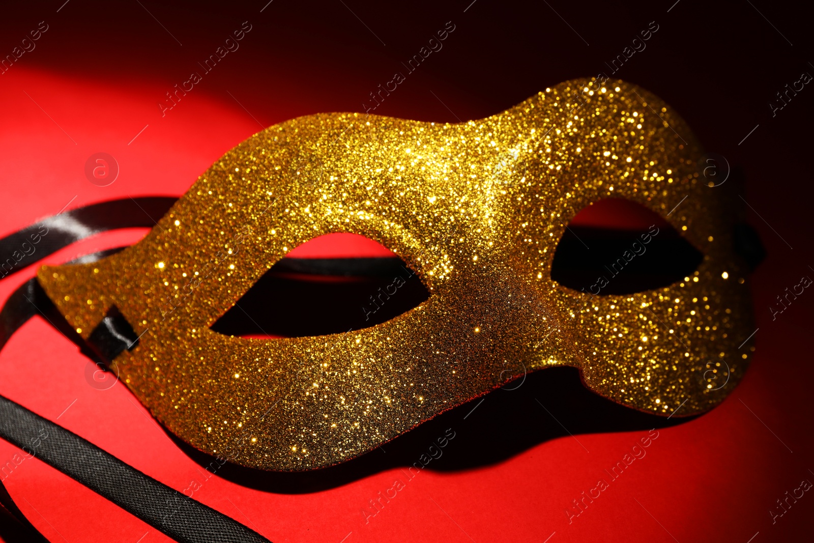 Photo of Beautiful golden carnival mask on red background, closeup