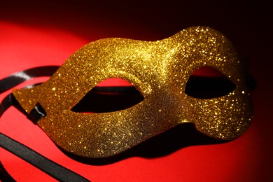 Photo of Beautiful golden carnival mask on red background, closeup