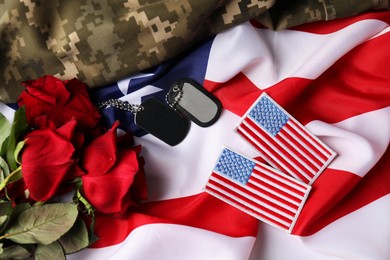 Photo of Veterans day. USA army patches, tokens, roses and military uniform on American flag, flat lay