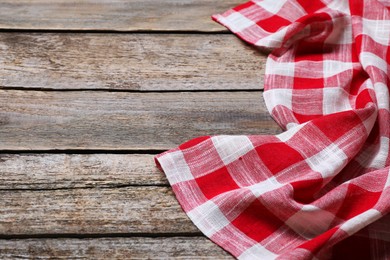 Photo of Crumpled tablecloth with checkered pattern on wooden table, space for text