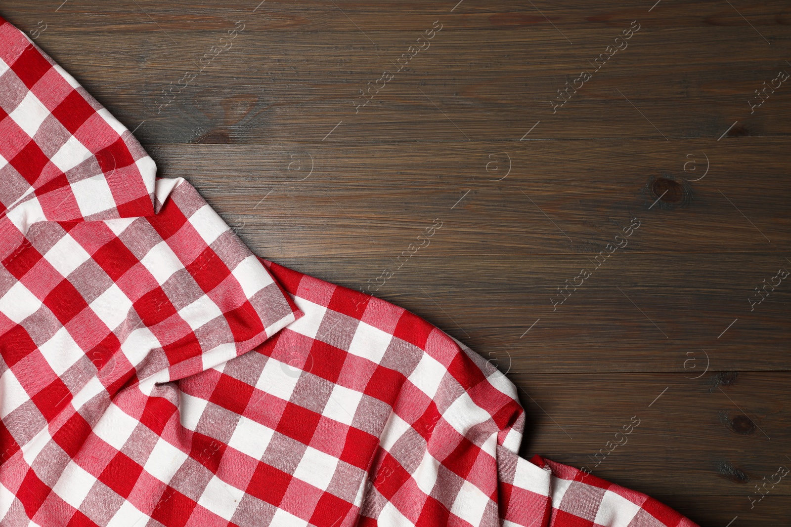 Photo of Crumpled tablecloth with checkered pattern on wooden table, top view. Space for text