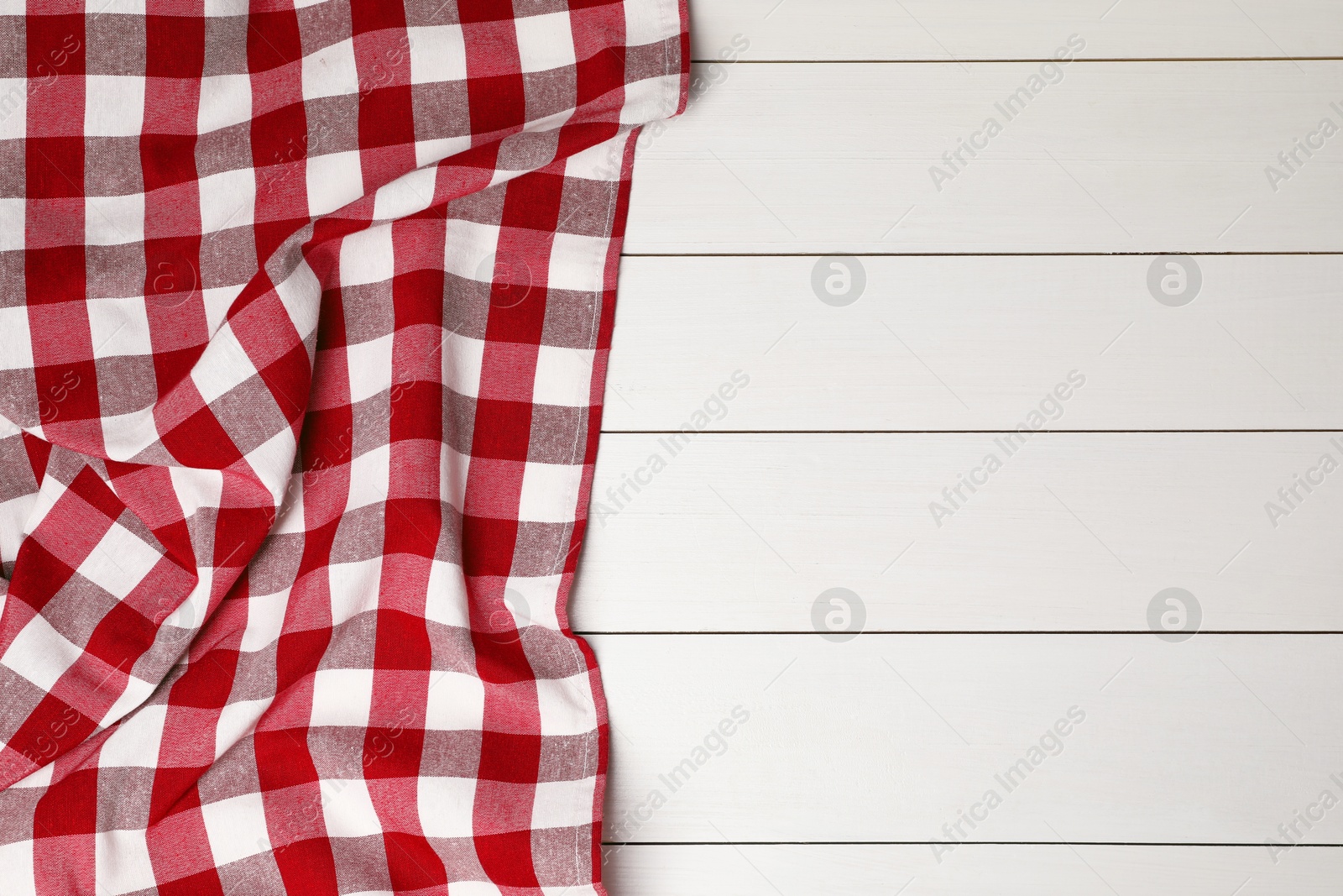 Photo of Crumpled tablecloth with checkered pattern on white wooden table, top view. Space for text