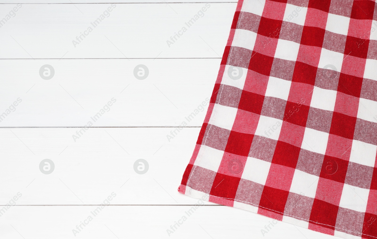 Photo of Tablecloth with checkered pattern on white wooden table, top view. Space for text