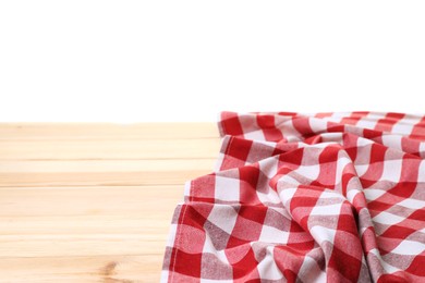 Crumpled tablecloth with checkered pattern on light wooden table against white background