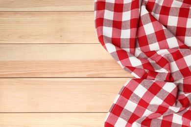 Photo of Crumpled tablecloth with checkered pattern on light wooden table, top view. Space for text