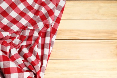 Crumpled tablecloth with checkered pattern on light wooden table, top view. Space for text