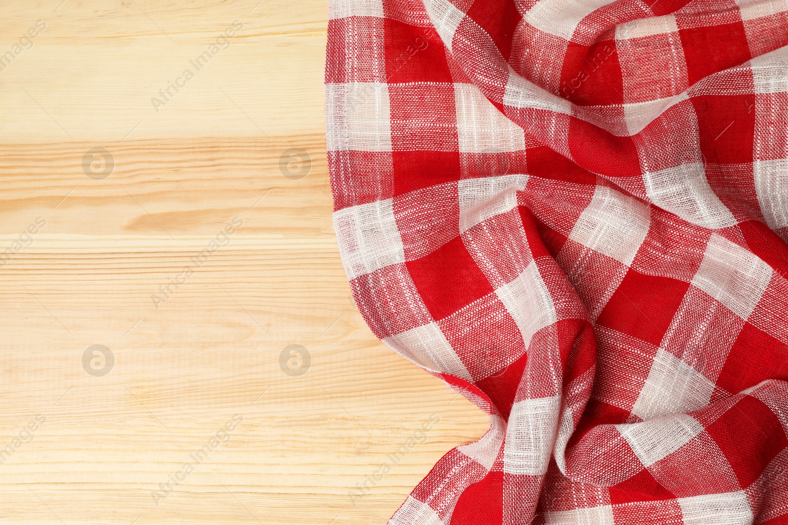 Photo of Crumpled tablecloth with checkered pattern on light wooden table, top view. Space for text