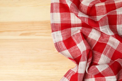 Crumpled tablecloth with checkered pattern on light wooden table, top view. Space for text