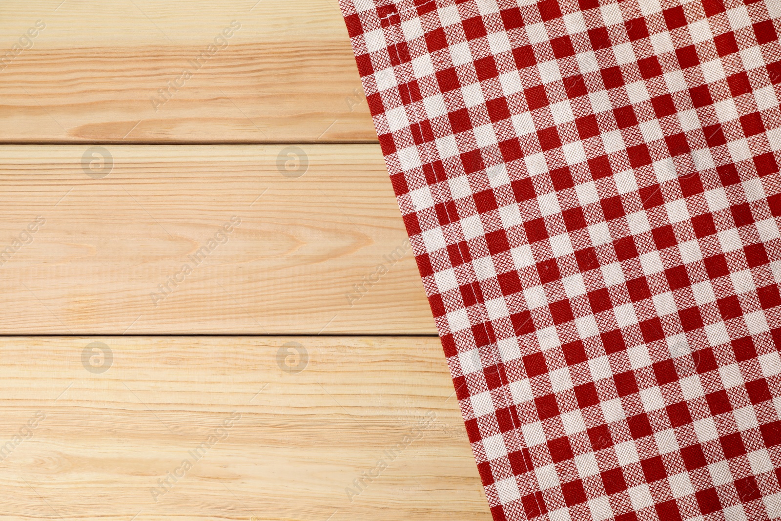 Photo of Tablecloth with checkered pattern on light wooden table, top view. Space for text