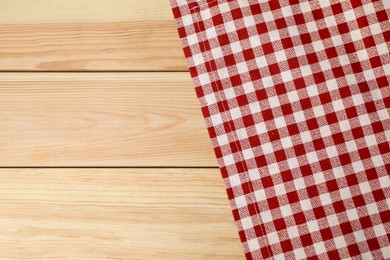 Photo of Tablecloth with checkered pattern on light wooden table, top view. Space for text