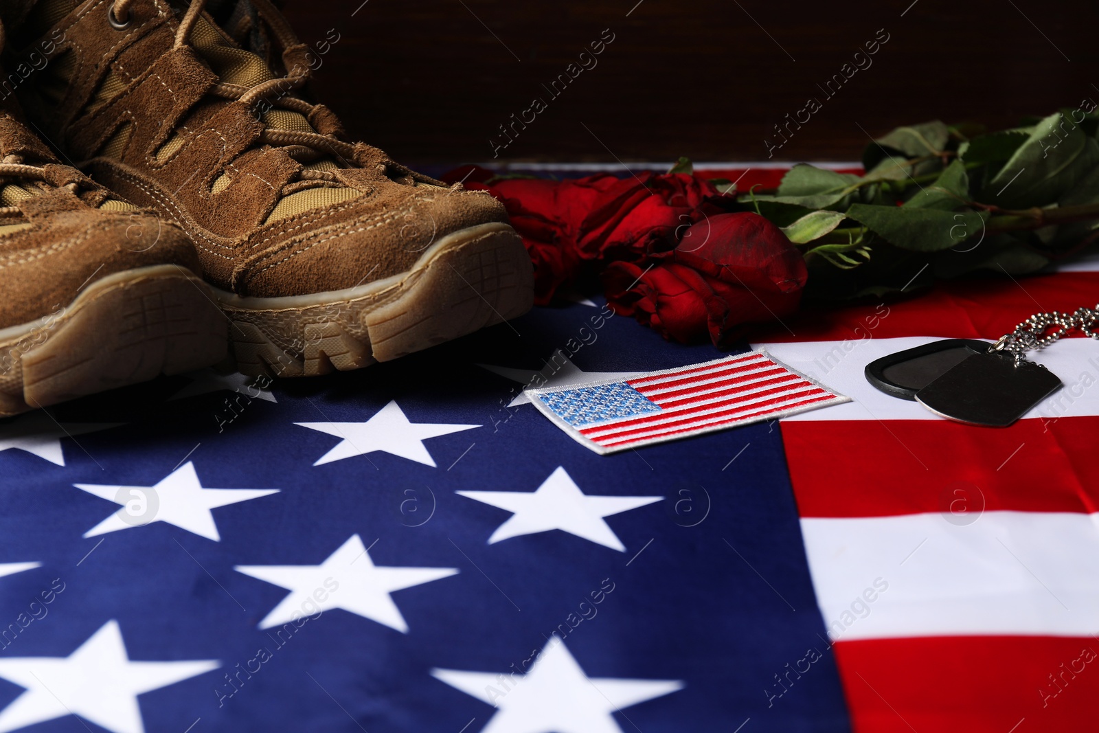 Photo of Veterans day. USA army patch, American flag, roses, tokens and military shoes, closeup