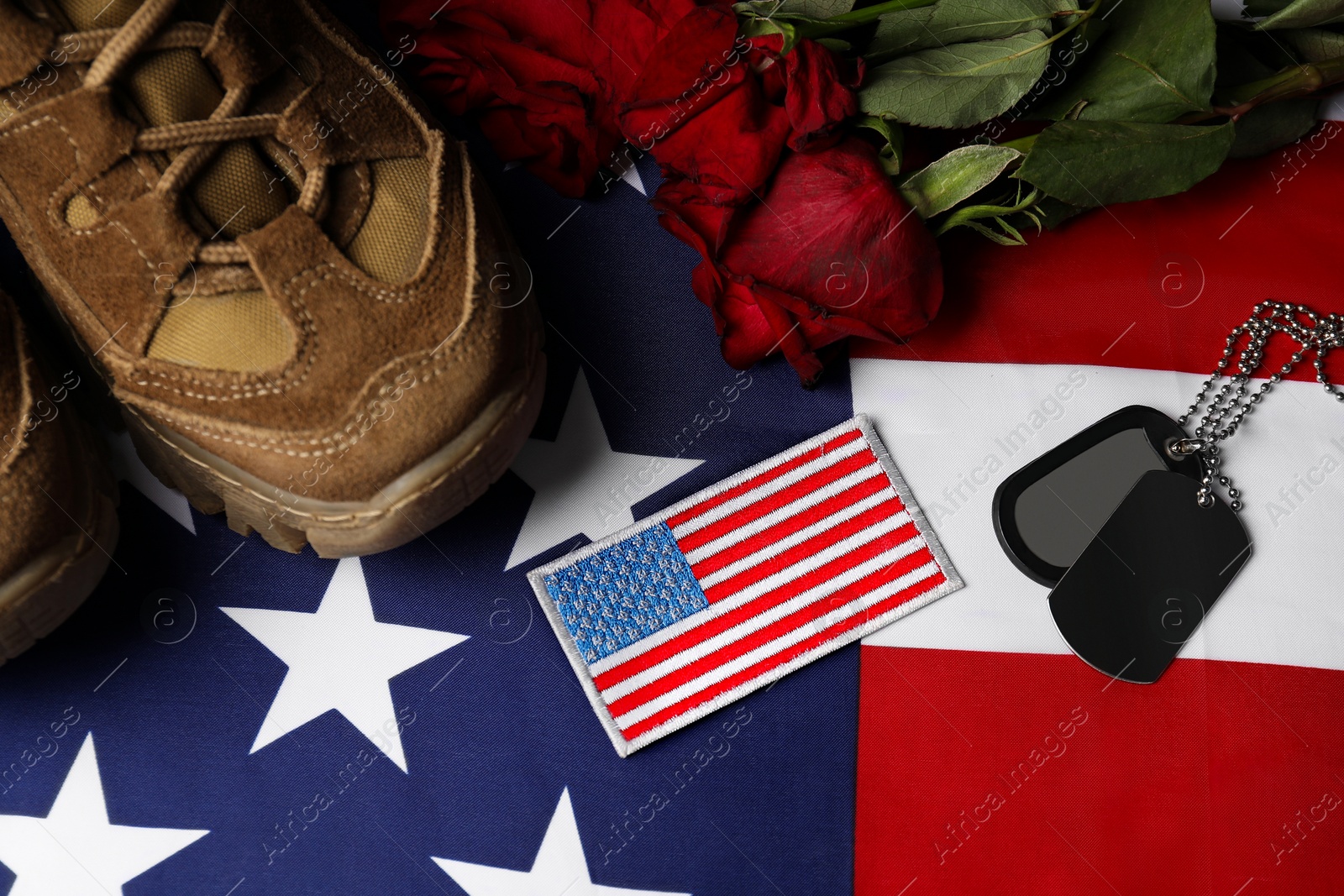 Photo of Veterans day. USA army patch, tokens, American flag, roses and military shoes, flat lay