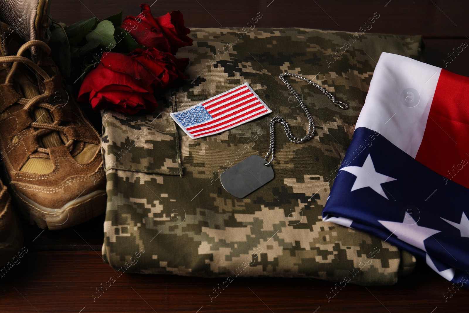 Photo of Veterans day. USA army patch, token, American flag, roses and military uniform on wooden table, closeup