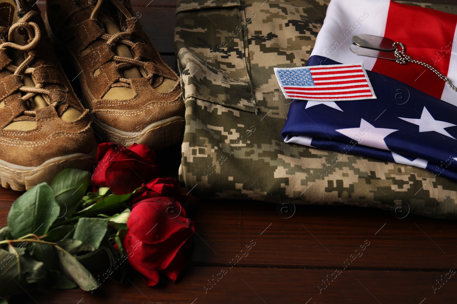 Photo of Veterans day. USA army patch, tokens, American flag, roses and military uniform on wooden table, closeup