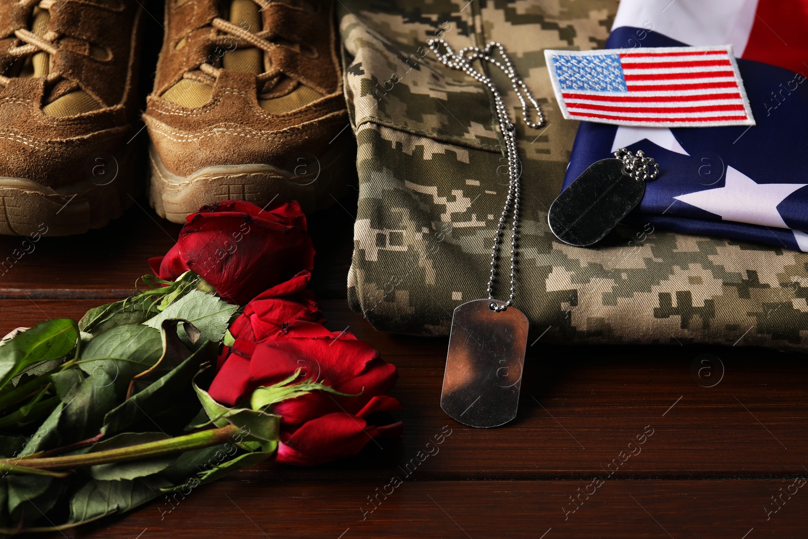 Photo of Veterans day. USA army patch, tokens, American flag, roses and military uniform on wooden table, above view