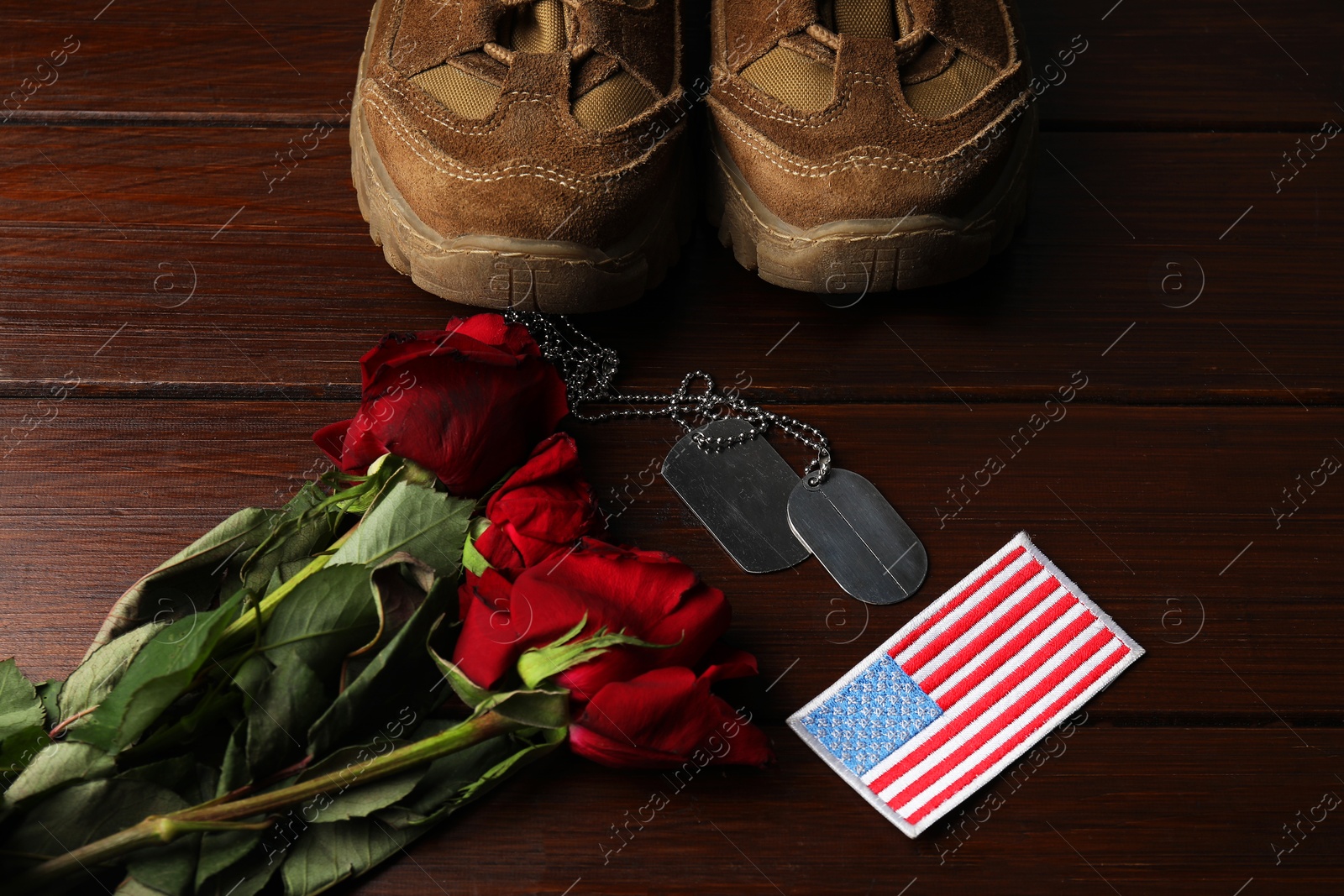 Photo of Veterans day. USA army patch, tokens, American flag, roses and military shoes on wooden table, above view