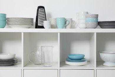 Photo of Storage cabinet with kitchenware near white wall indoors