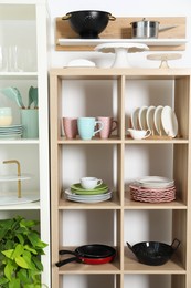 Shelving units with kitchenware near white wall indoors