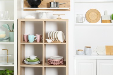 Photo of Shelving units with kitchenware near white wall indoors