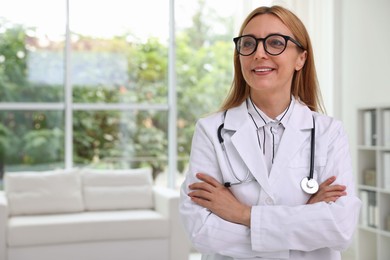 Smiling doctor with stethoscope in clinic, space for text