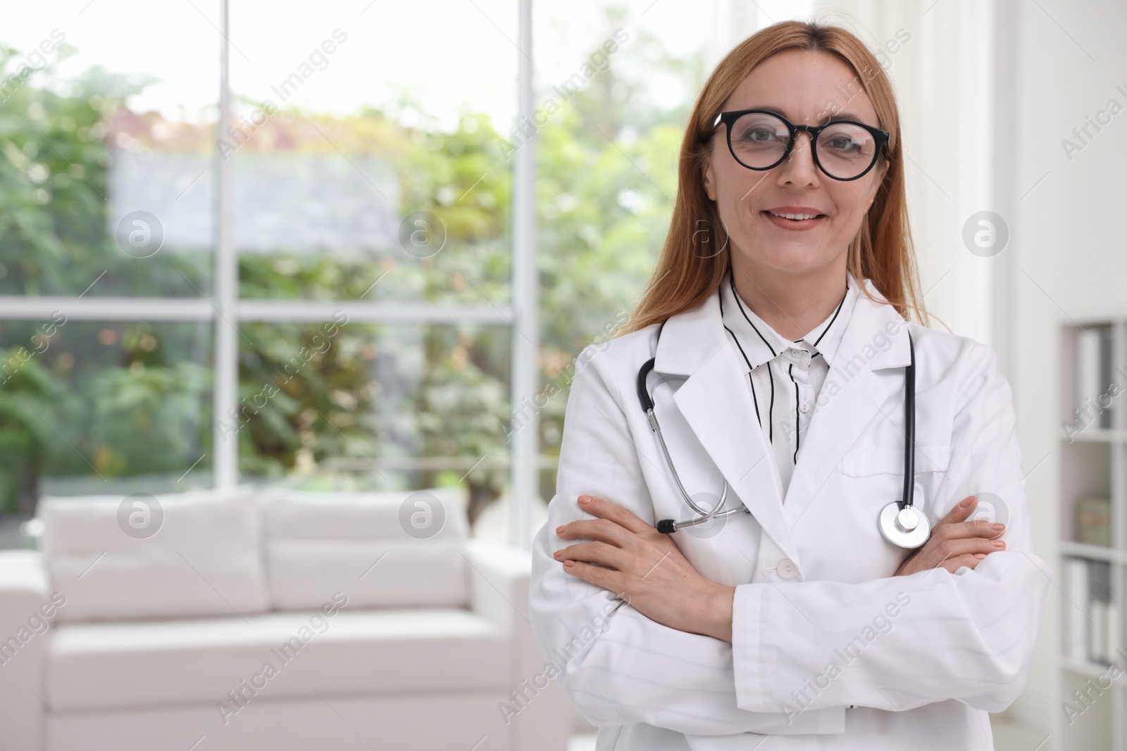 Photo of Smiling doctor with stethoscope in clinic, space for text